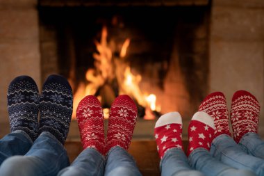 Noel çoraplı aile şöminenin yanında. Anne, baba ve çocuklar birlikte eğleniyorlar. İnsanlar evde dinleniyor. Kış tatili Xmas ve Yeni Yıl konsepti