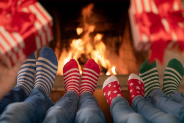Noel çoraplı aile şöminenin yanında. Anne, baba ve çocuklar birlikte eğleniyorlar. İnsanlar evde dinleniyor. Kış tatili Xmas ve Yeni Yıl konsepti