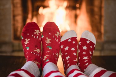Şöminenin yanındaki Noel çoraplı çift. Erkek ve kadın birlikte eğleniyor. İnsanlar evde dinleniyor. Kış tatili Xmas ve Yeni Yıl konsepti