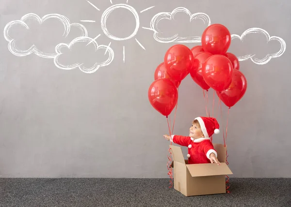 クリスマスの衣装を着た幸せな子供 赤い風船で箱の中に座っている子供 面白い子供が遊んでる クリスマス休暇を楽しんでいる子供 — ストック写真