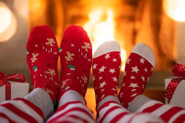 Şöminenin yanındaki Noel çoraplı çift. Erkek ve kadın birlikte eğleniyor. İnsanlar evde dinleniyor. Kış tatili Xmas ve Yeni Yıl konsepti