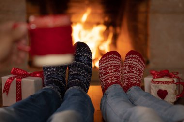 Şöminenin yanındaki Noel çoraplı çift. Erkek ve kadın birlikte eğleniyor. İnsanlar evde dinleniyor. Kış tatili Xmas ve Yeni Yıl konsepti