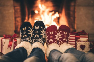 Şöminenin yanındaki Noel çoraplı çift. Erkek ve kadın birlikte eğleniyor. İnsanlar evde dinleniyor. Kış tatili Xmas ve Yeni Yıl konsepti