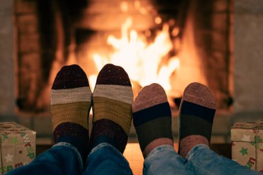 Şöminenin yanındaki Noel çoraplı çift. Erkek ve kadın birlikte eğleniyor. İnsanlar evde dinleniyor. Kış tatili Xmas ve Yeni Yıl konsepti