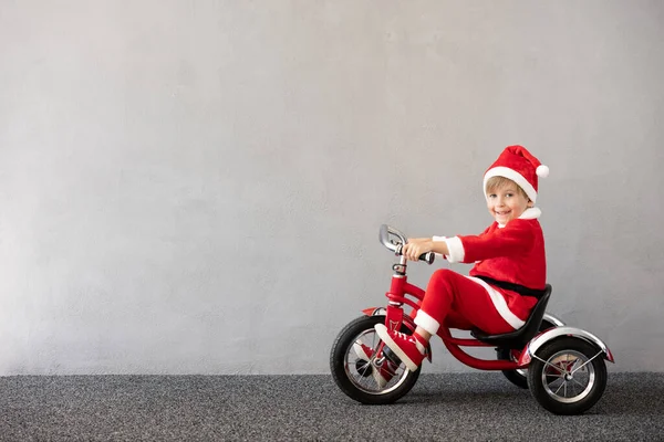 クリスマスの衣装を着た幸せな子供 子供用自転車 面白い子供が遊んでる 子供は冬にアウトドアを楽しんでいます クリスマス休暇のコンセプト — ストック写真