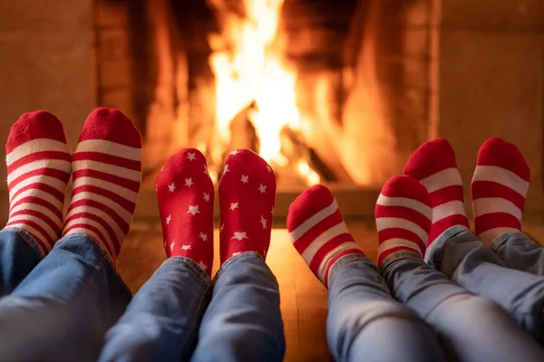 暖炉の近くのクリスマスソックスの家族 お母さん お父さんとお子さんが一緒に楽しんでいます 家でリラックスしてる 冬の休日クリスマスと新年のコンセプト — ストック写真