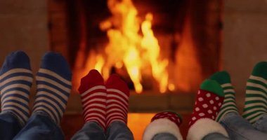 Noel çoraplı aile şöminenin yanında. Anne, baba ve çocuklar birlikte eğleniyorlar. İnsanlar evde dinleniyor. Kış tatili Xmas ve Yeni Yıl konsepti