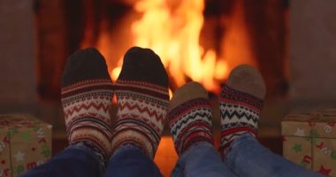 Şöminenin yanındaki Noel çoraplı çift. Erkek ve kadın birlikte eğleniyor. İnsanlar evde dinleniyor. Kış tatili Xmas ve Yeni Yıl konsepti