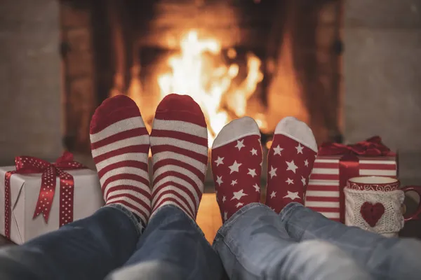 暖炉の近くのクリスマスソックスのカップル 男と女が一緒に楽しんでる 家でリラックスしてる 冬の休日クリスマスと新年のコンセプト — ストック写真