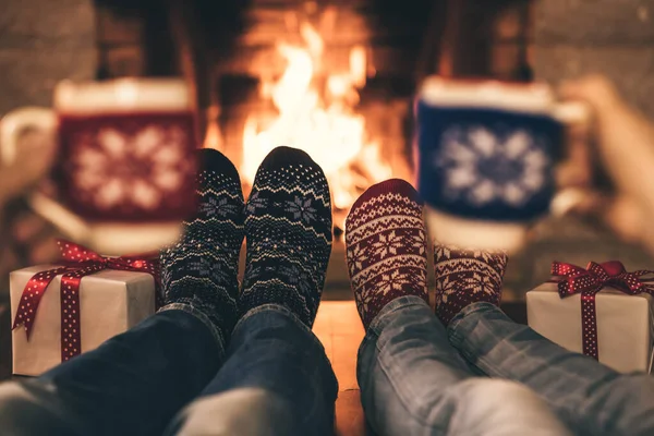 Couple in Christmas socks near fireplace. Man and woman having fun together. People relaxing at home. Winter holiday Xmas and New Year concept