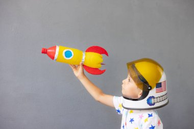 Mutlu çocuk beton duvar arkasında oyuncak roketle oynuyor. Çocuk astronot gibi davranıyor. Hayal gücü ve çocuklar rüya görür.