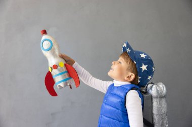 Mutlu çocuk beton duvar arkasında oyuncak roketle oynuyor. Çocuk astronot gibi davranıyor. Hayal gücü ve çocuklar rüya görür.
