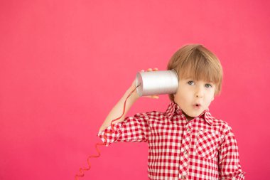 Elinde oyuncak telefon tutan mutlu çocuk. Pembe arka planda gülümseyen çocuk portresi. Sevgililer Günü Tatil Konsepti