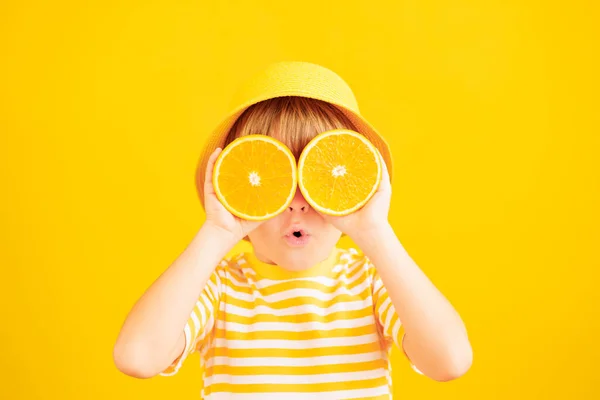 高傲的孩子手里拿着像太阳镜一样的橘子片 孩子穿着条纹黄色的T恤 背景是纸的 健康饮食和暑假概念 — 图库照片