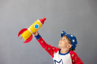 Mutlu çocuk beton duvar arkasında oyuncak roketle oynuyor. Çocuk astronot gibi davranıyor. Hayal gücü ve çocuklar rüya görür.