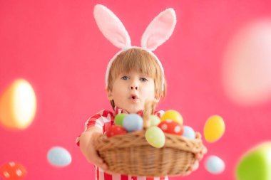 Sürpriz çocuk elinde paskalya yumurtalarıyla sepeti tutuyor. Paskalya tavşanı takan komik çocuk. Çocuk evde eğleniyor. Bahar tatili kavramı
