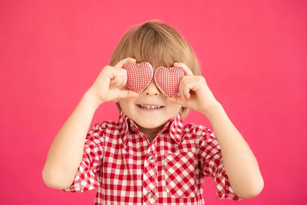 幸せな子供の手に心を保持する ピンクの背景に笑顔の子供の肖像画 バレンタインデーの休暇のコンセプト — ストック写真