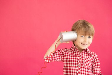 Elinde oyuncak telefon tutan mutlu çocuk. Pembe arka planda gülümseyen çocuk portresi. Sevgililer Günü Tatil Konsepti