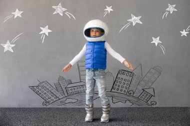 Mutlu çocuk beton duvar arkasında oyuncak roketle oynuyor. Çocuk astronot gibi davranıyor. Hayal gücü ve çocuklar rüya görür.