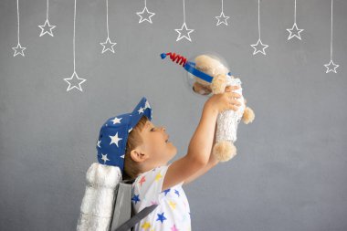Mutlu çocuk oyuncak roketle oynuyor. Oyuncak ayıyı beton duvara dayayan bir çocuk. Çocuk astronot gibi davranıyor. Hayal gücü ve çocuklar rüya görür.