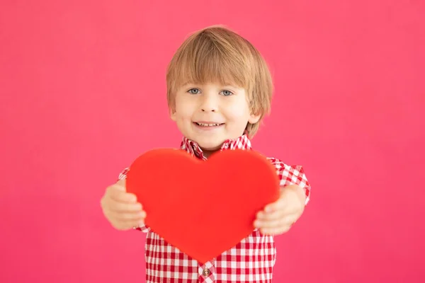 幸せな子供の手に心を保持する ピンクの背景に笑顔の子供の肖像画 バレンタインデーの休暇のコンセプト — ストック写真