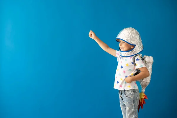 青い背景におもちゃのロケットで遊ぶ幸せな子供 子供は宇宙飛行士のふりをする 想像力と子供の夢のコンセプト — ストック写真