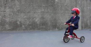 Mutlu çocuk iş adamı gibi davranıyor. Komik çocuk dışarıda trike kullanıyor. İşine dön, işe başla ve iş fikri kavramına dön. Yavaş çekim 4K