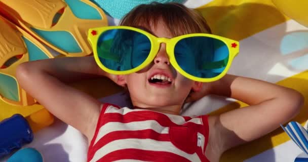 Szczęśliwe Dziecko Olbrzymich Okularach Zabawny Dzieciak Leżący Żółtym Ręczniku Paski — Wideo stockowe
