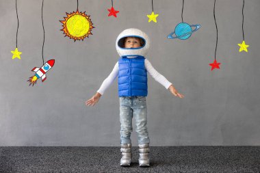 Mutlu çocuk beton duvar arkasında oyuncak roketle oynuyor. Çocuk astronot gibi davranıyor. Hayal gücü ve çocuklar rüya görür.
