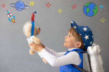 Mutlu çocuk oyuncak roketle oynuyor. Oyuncak ayıyı beton duvara dayayan bir çocuk. Çocuk astronot gibi davranıyor. Hayal gücü ve çocuklar rüya görür.
