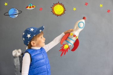 Mutlu çocuk beton duvar arkasında oyuncak roketle oynuyor. Çocuk astronot gibi davranıyor. Hayal gücü ve çocuklar rüya görür.