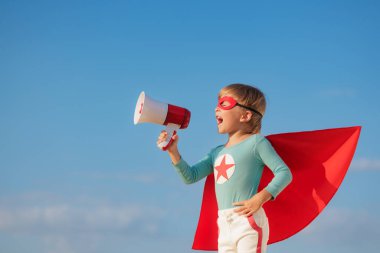 Dışarıda hoparlörden bağıran süper kahraman çocuk. Mavi yaz gökyüzü geçmişine karşı süper kahraman çocuk. Hayal gücü ve özgürlük kavramı