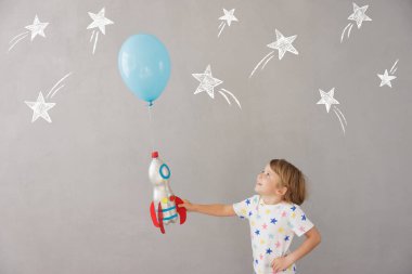 Evde oyuncak roketle oynayan mutlu çocuk. Çocuk astronot gibi davranıyor. Hayal gücü ve çocuklar rüya görür.