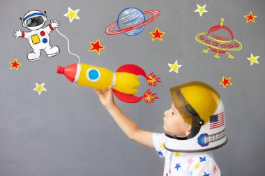 Mutlu çocuk beton duvar arkasında oyuncak roketle oynuyor. Çocuk astronot gibi davranıyor. Hayal gücü ve çocuklar rüya görür.