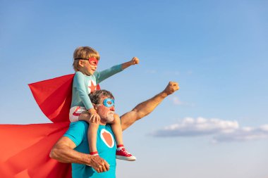 Süper kahraman kıdemli adam ve çocuk dışarıda oynuyorlar. Süper kahraman büyükbaba ve çocuk mavi gökyüzü geçmişine karşı birlikte eğleniyorlar. Aile tatili konsepti. Babalar günün kutlu olsun.