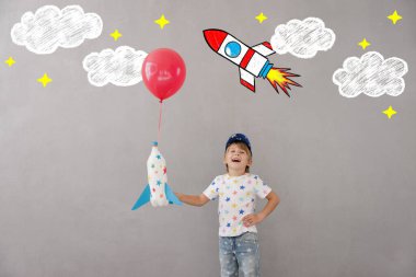 Evde oyuncak roketle oynayan mutlu çocuk. Çocuk astronot gibi davranıyor. Hayal gücü ve çocuklar rüya görür.