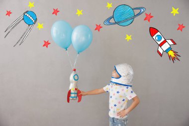 Evde oyuncak roketle oynayan mutlu çocuk. Çocuk astronot gibi davranıyor. Hayal gücü ve çocuklar rüya görür.
