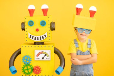 Sarı arka planda robotu olan mutlu çocuk. Evde oynayan komik çocuk. Başarı, yaratıcı ve yenilikçi teknoloji kavramı
