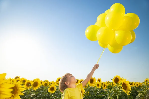快乐的孩子在春天的向日葵地里玩得很开心 蓝色天空背景下 带着彩色气球的孩子的户外肖像 — 图库照片