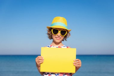 Yaz tatilinde elinde kağıt tutan çocuk. Kız sahilde eğleniyor. Seyahat ve macera konsepti