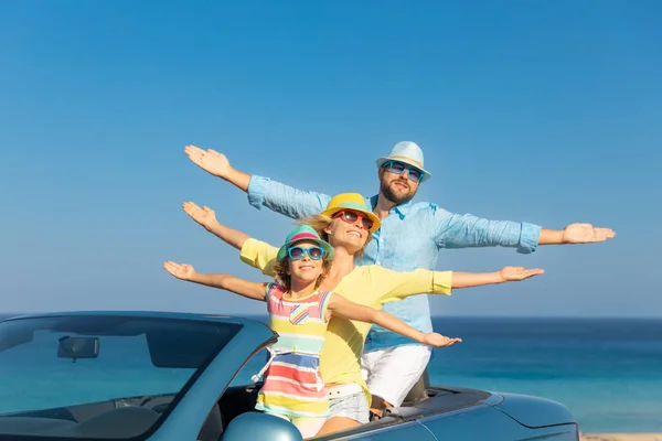 Happy family travel by car at the sea. Mother, father and daughter having fun in blue cabriolet. Summer vacation concept