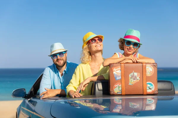 Happy family travel by car at the sea. Mother, father and daughter having fun in blue cabriolet. Summer vacation concept