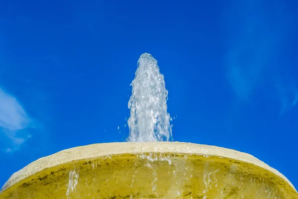 Fountain basin and vertical jet of water against blue sky