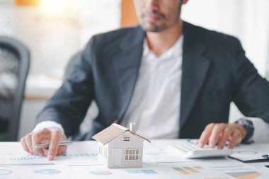 Cropped shot of estate agent using calculator calculate for contract to buy or sell house, mortgage loan or home insurance in the office.