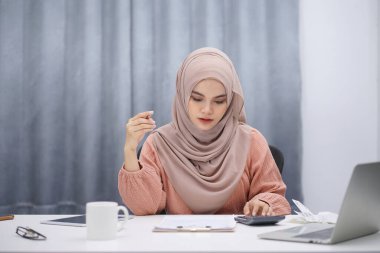 Stressed muslim woman calculating monthly financial, plan budget on computer, pay bills or taxes online at home