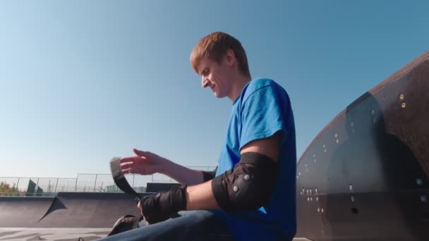 Hombre en skate park pone en protección de la muñeca — Vídeo de stock