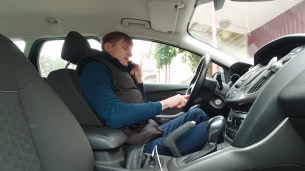 Мужчина разговаривает по телефону в машине — стоковое видео