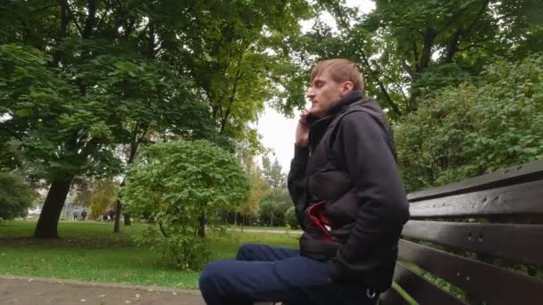 Mężczyzna rozmawia przez telefon w parku — Wideo stockowe