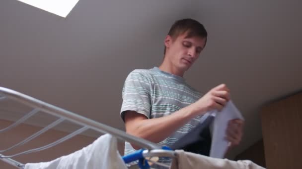 Een man vouwt droge kleren — Stockvideo