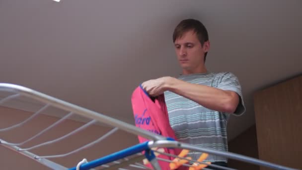 Egy férfi, aki felakasztja a ruháit — Stock videók
